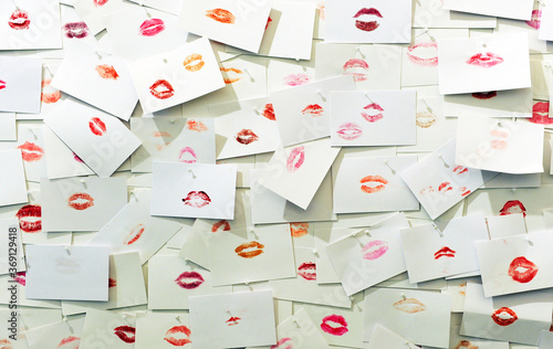 Many mouths with red lips painted with lipstick printed on white paper cards. Messages of love and affection concept. Loving background kisses