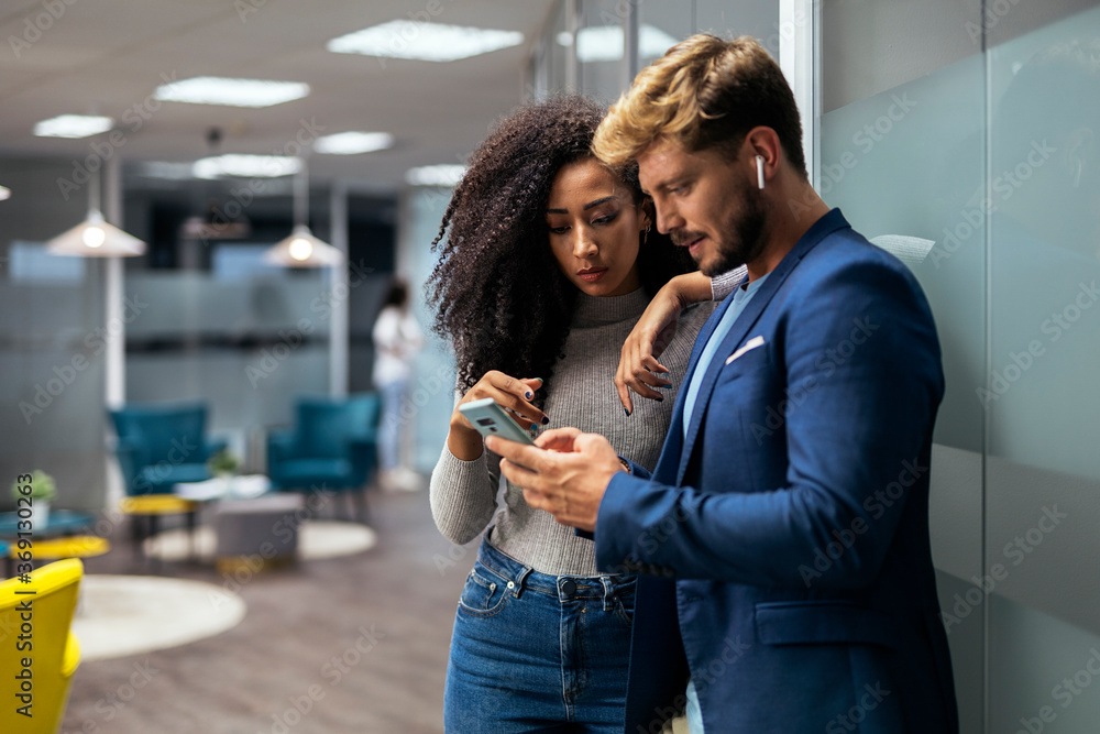 © Santi Nunez/Stocksy - young modern people in smart casual wear discussing business an looking at screen phone for a project © Santi Nunez/Stocksy - young modern people in smart casual wear discussing business an looking at screen phone for a project