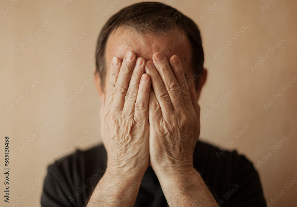 senior man covering his face by hands senior man covering his face by hands