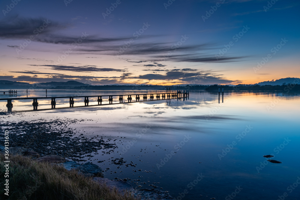 Wharf, reflections and sunrise over the bay