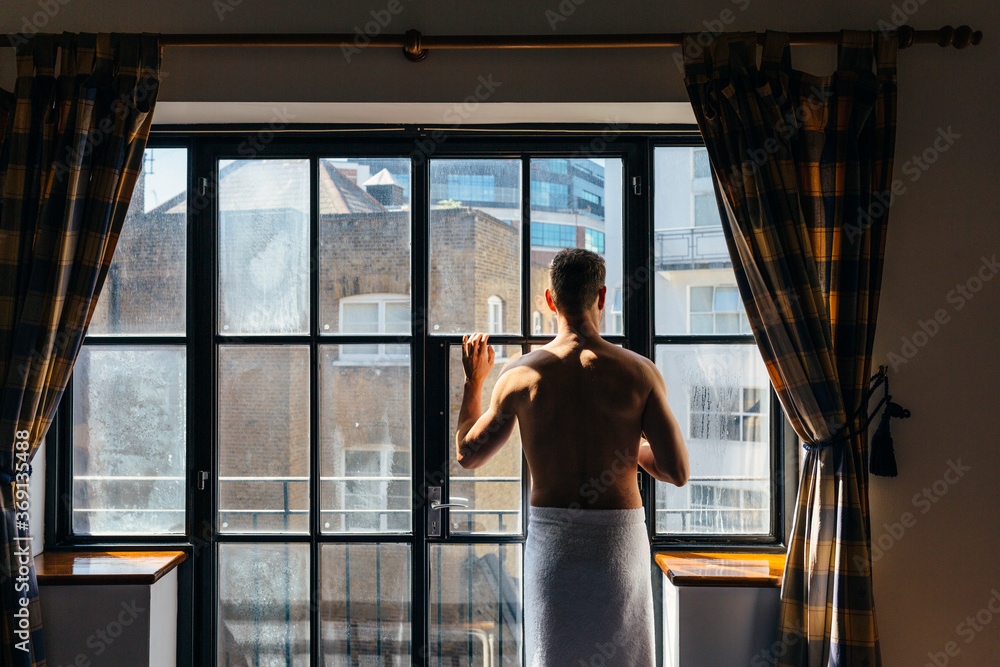 Adult man enjoying the sun rays besides the window in the morning Adult man enjoying the sun rays besides the window in the morning