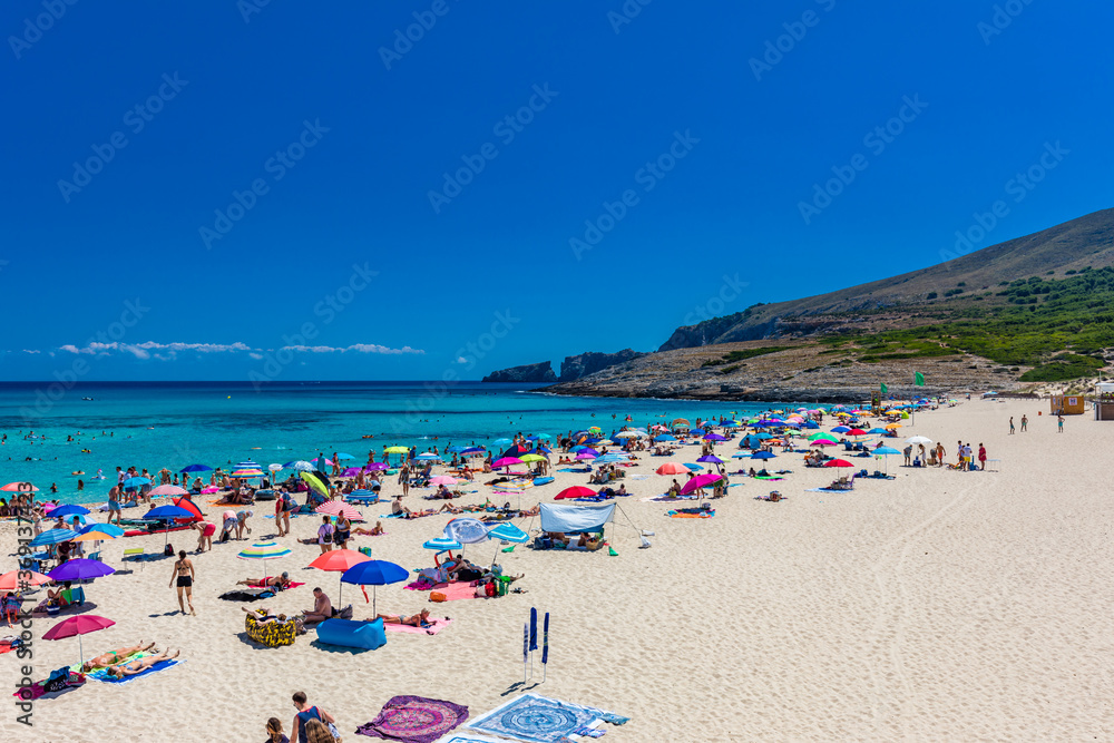 CALA MESQUIDA, MALLORCA, SPAIN - 19 July 2020: People enjoying beautiful sandy beach of on Mallorca, Mediterranean Sea, Spain. CALA MESQUIDA, MALLORCA, SPAIN - 19 July 2020: People enjoying beautiful sandy beach of on Mallorca, Mediterranean Sea, Spain.
