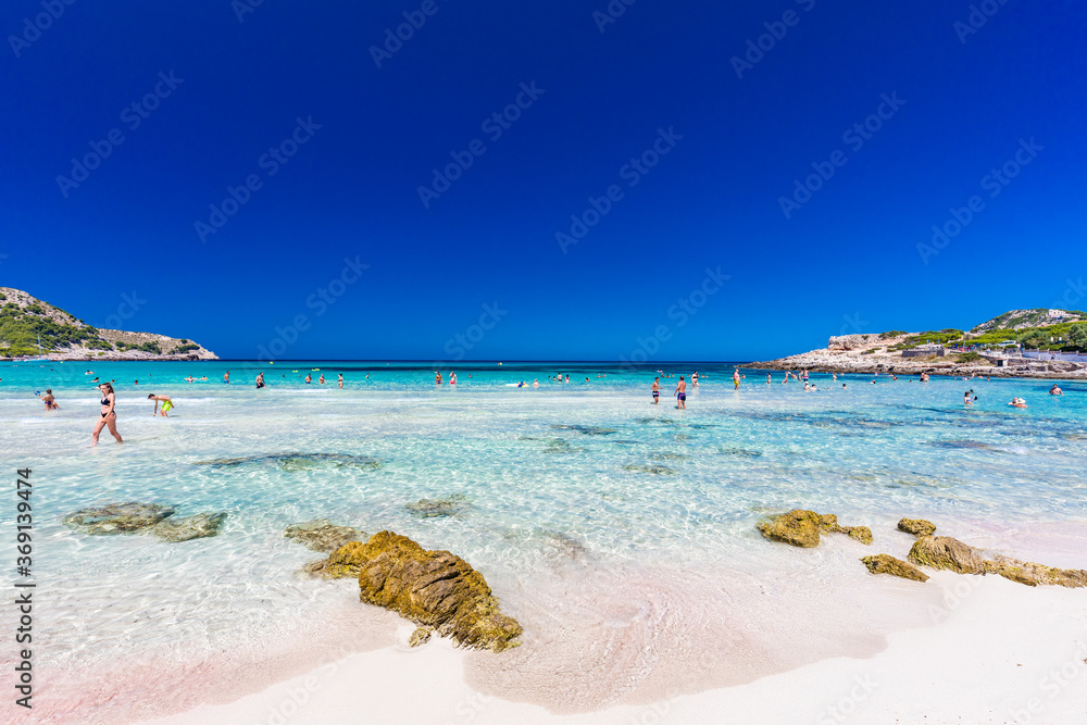 Naklejka premium CALA AGULLA, MALLORCA, SPAIN - 21 July 2020: People enjoying summer on the popular beach on Mallorca, Balearic Islands.