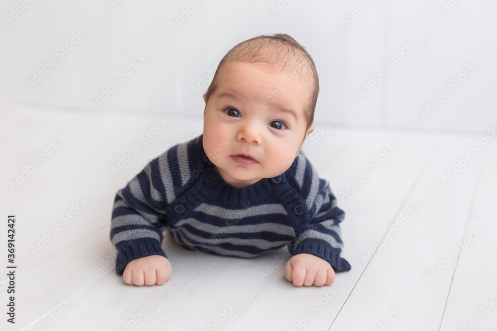 baby in a striped jacket on a white background. a three-month-old boy. children's photo session baby in a striped jacket on a white background. a three-month-old boy. children's photo session