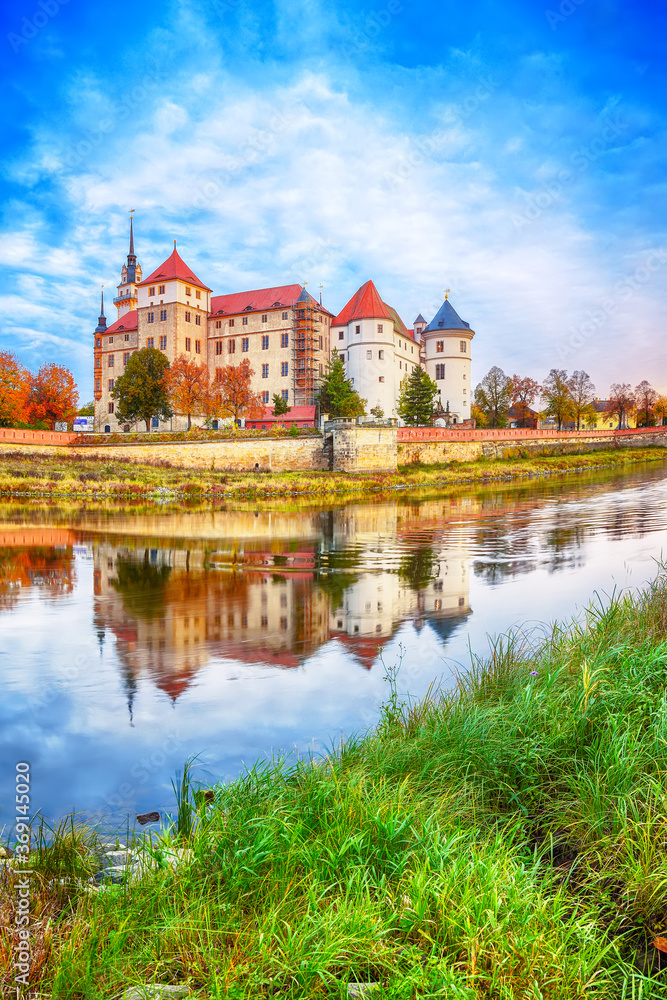 Picturesque morning view of Hartenfels castle on banks of the Elbe. Dramatic sunrise