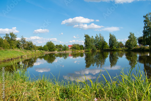 Lake in the village. The sky is reflected in the water. Summer