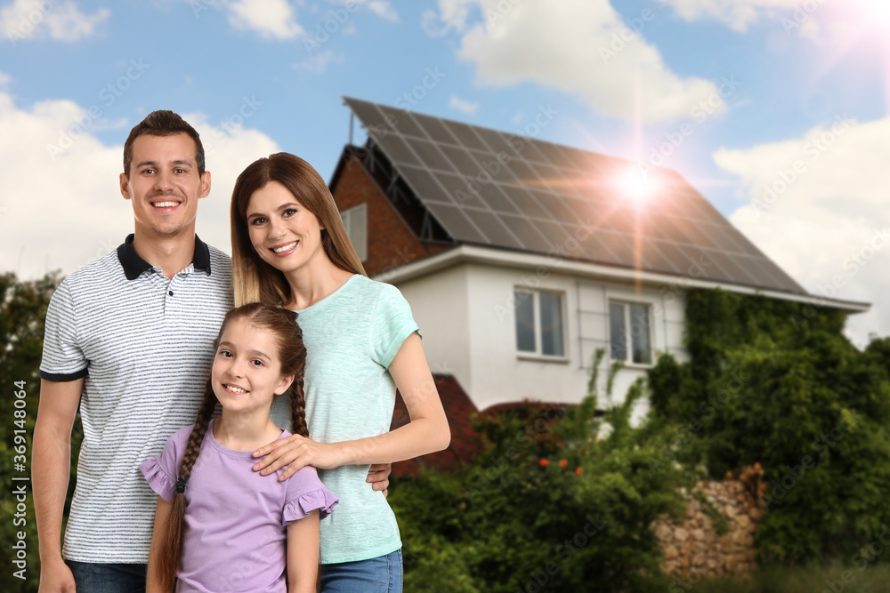 Happy family near their house with solar panels. Alternative energy source