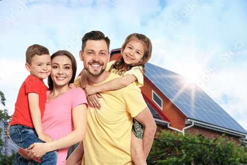 Happy family near their house with solar panels. Alternative energy source