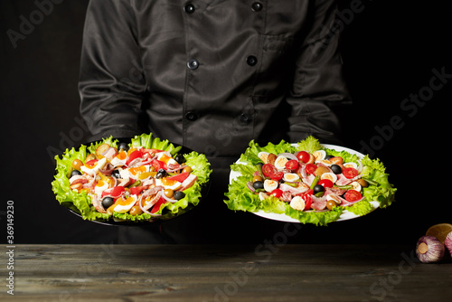 Fototapeta Naklejka Na Ścianę i Meble -  A male chef holds two bowls of tuna salad (Nicoise).