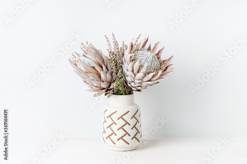 Beautiful floral arrangement including beautiful dried pink King Proteas and delicate thryptomene flowers, in a stylish aztec vase. photo