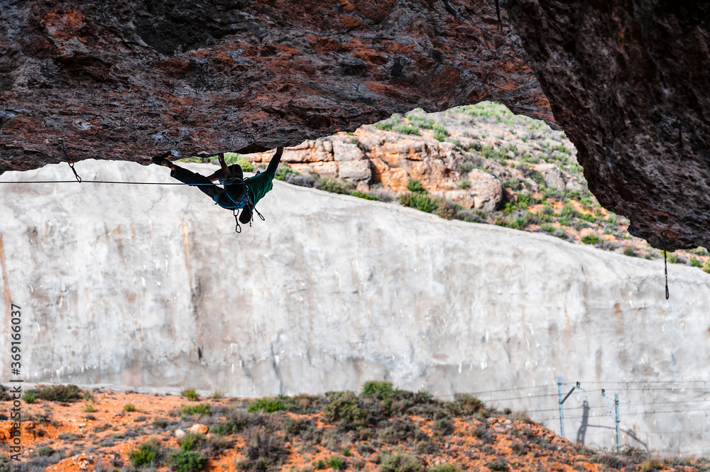 Climber ascending from fhe rooftop of a cave Climber ascending from fhe rooftop of a cave