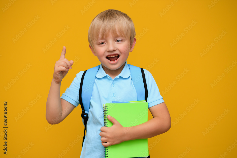 Portrait of a cute schoolboy boy 6 years old with a bright backpack on a yellow background. Back to school. Portrait of a cute schoolboy boy 6 years old with a bright backpack on a yellow background. Back to school.
