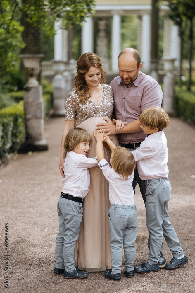 Father and sons touching belly of pregnant mother Father and sons touching belly of pregnant mother