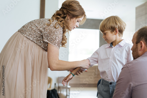 Mother helping son with shirt before party photo