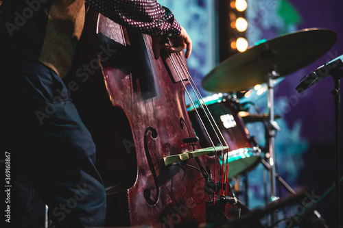 Concert view of a contrabass violoncello player with vocalist and musical during jazz orchestra band performing music, violoncellist cello player on stage photo