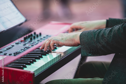 Concert view of a musical keyboard piano player during musical jazz band orchestra performing, keyboardist hands during concert, male pianist on stage, hands close up