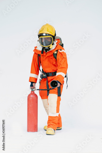 A portrait of Asian male firefighter in red protective uniform, mask and helmet with fire extinguisher standing on white background.