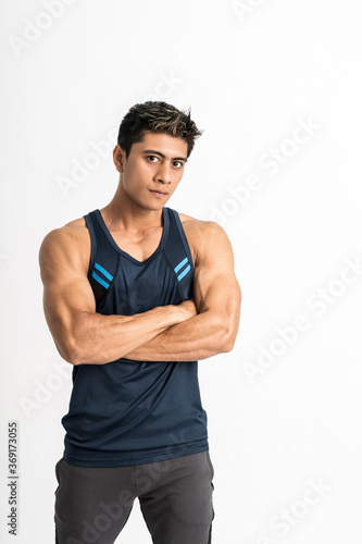 muscular man standing wearing gym clothes with crossed hands looking at the camera on an isolated background