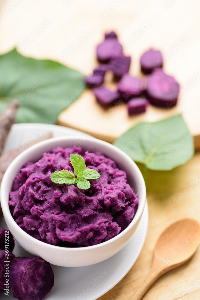 Mashed purple sweet potatoes in a bowl with spoon on wooden table, Healthy food Mashed purple sweet potatoes in a bowl with spoon on wooden table, Healthy food