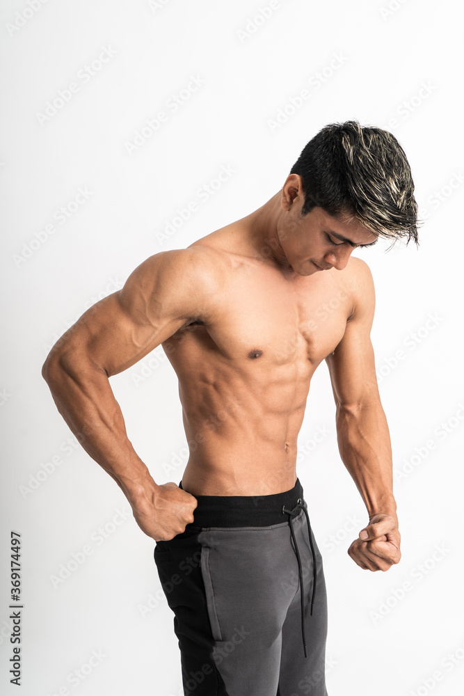 man showing muscular abdomen and chest with one hand on waist stand facing side on isolated background