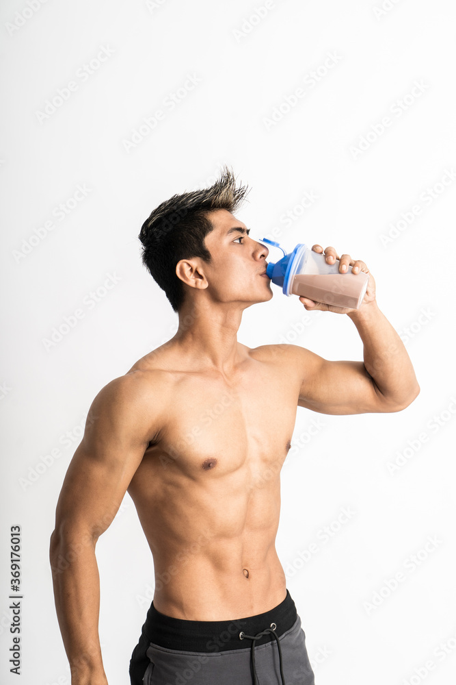 young man with muscular body holding a bottle and drink with one hand stand facing side on isolated background young man with muscular body holding a bottle and drink with one hand stand facing side on isolated background