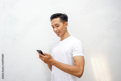 Asian man holding smartphone and happy about his business or online shop  © Habib