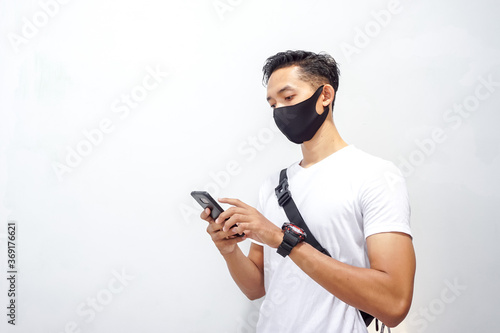 Asian man wearing mask and holding smartphone 