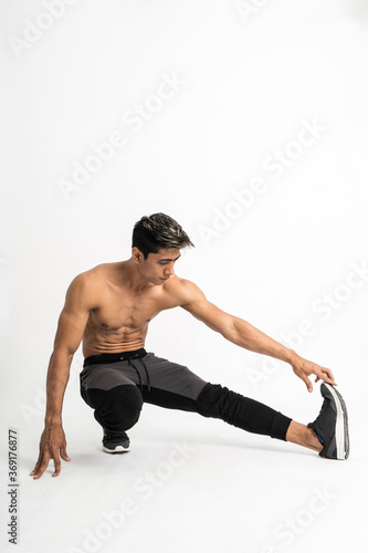 full body image of muscle man without clothes do leg stretching by squat one leg pulled forward on an isolated background