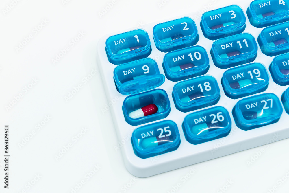 Red capsule medicine in the monthly pill organizer. The concept of dose scheduler for elder patients Red capsule medicine in the monthly pill organizer. The concept of dose scheduler for elder patients