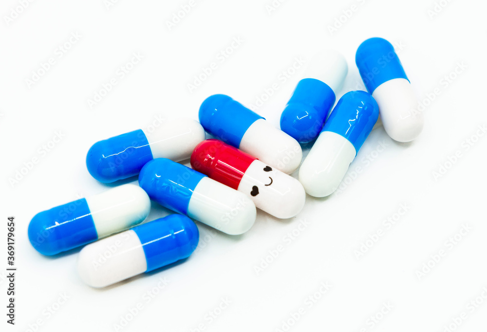 Smiling face red capsule medicine with blue normal capsules on the white background. The concept of a novel drug development against rare diseases Smiling face red capsule medicine with blue normal capsules on the white background. The concept of a novel drug development against rare diseases