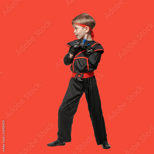 Young boy training karate martial art isolated on red background