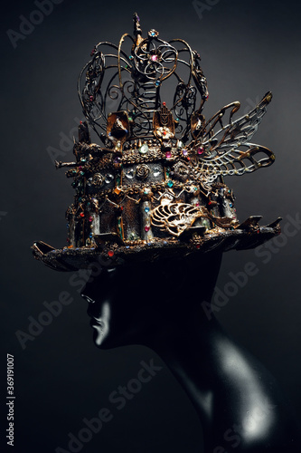 Mannequin in top-hat with wings and crown on black background