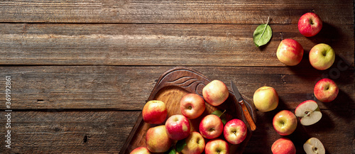 Red apple and wooden board on rustic wooden background. Ripe apples on vintage table and copy space. Summer or autumn season.