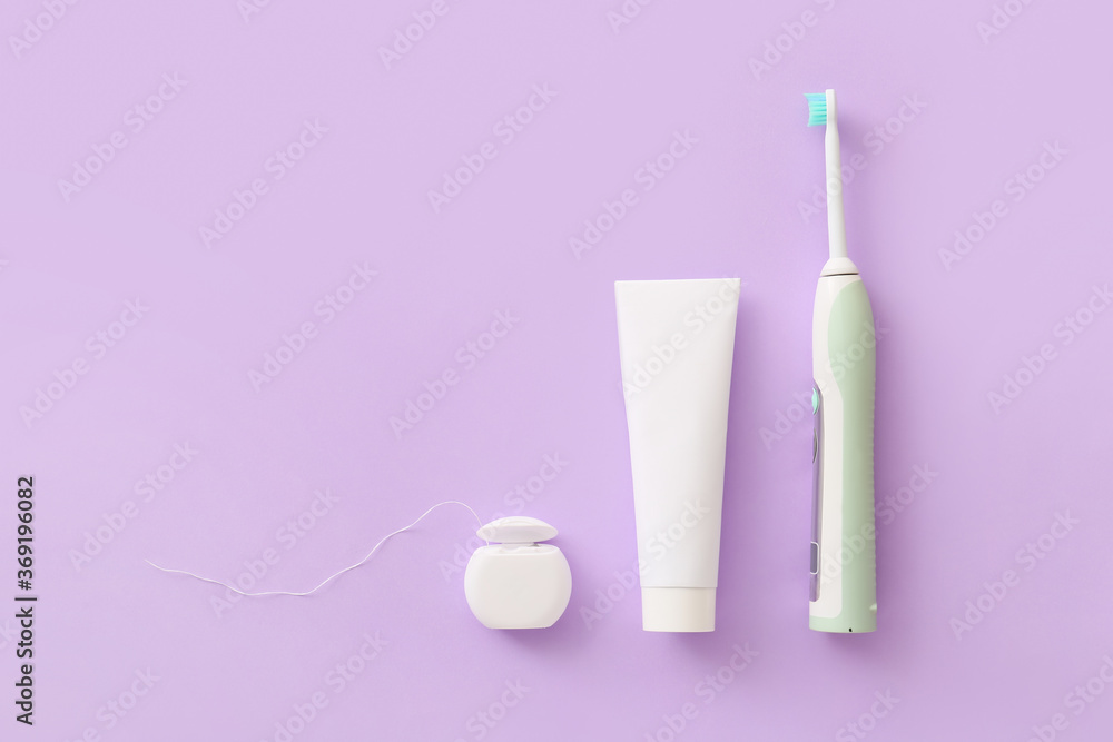 Electric tooth brush, paste and floss on color background