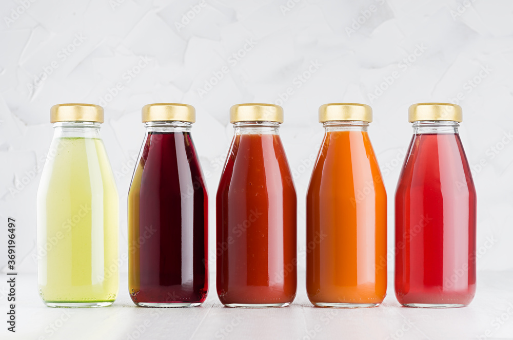 Vegetable and fruit juices large set in glass bottles with cap mock up in row on white wood table in light interior, template for packaging, advertising, design product, branding.