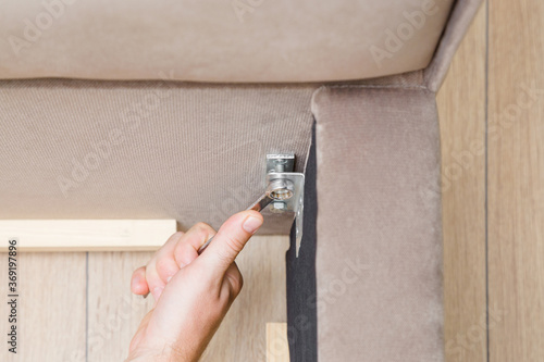 Foto Young man hand using wrench and screwing screw in metal steel angle connector in corner of bed