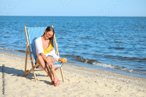 Beautiful young woman applying sunscreen cream on sea beach