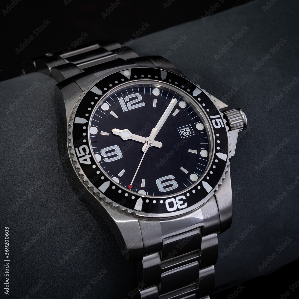 Watch in a studio shot with highly controlled lighting. The watch is used and has a black dial and steel bracelet. Watch in a studio shot with highly controlled lighting. The watch is used and has a black dial and steel bracelet.