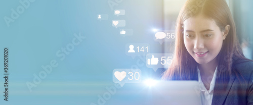 Businesswoman smiling and using laptop with social media or marketing concept  with blue tone. photo
