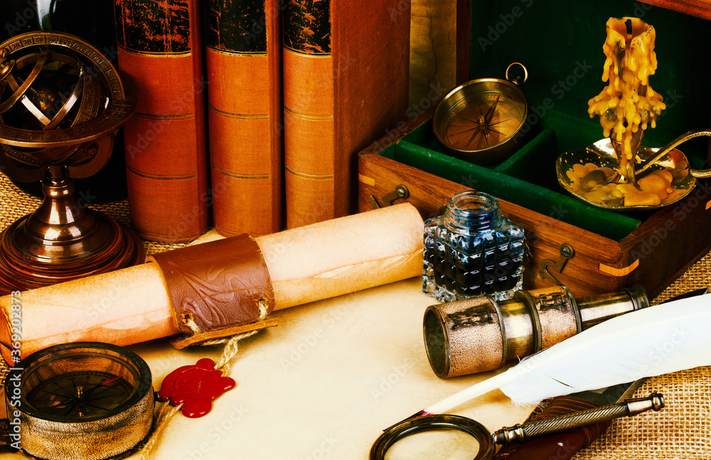 Old books, feather pen and ink bottle, old scroll with red wax seal, vintage compass. Adventure stories background.