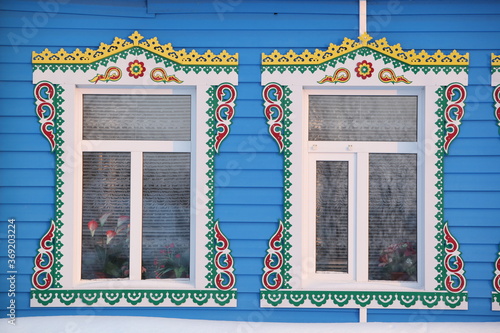 Richly decorated ornamental carved windows and frames on vintage wooden rural house in village in Ulyanovsk region, Russia. Russian traditional national folk style in wooden architecture. Countryside photo