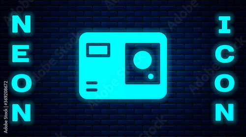 Glowing neon Action extreme camera icon isolated on brick wall background. Video camera equipment for filming extreme sports. Vector Illustration.