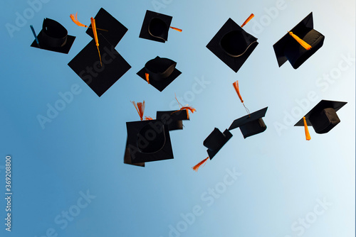 Graduates throw black hats in the sky.