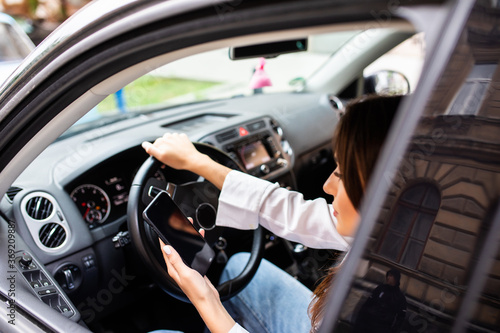 Young woman using smartphone while driving car