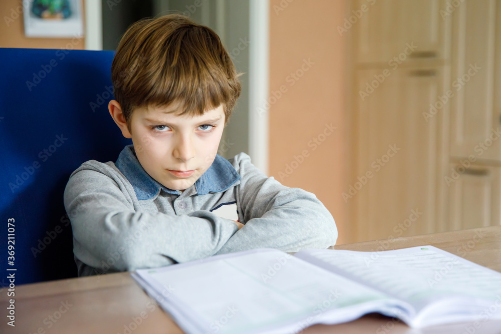Upset school kid boy making homework during quarantine time from corona pandemic disease. Crying and sad boy frustrating staying at home. Upset school kid boy making homework during quarantine time from corona pandemic disease. Crying and sad boy frustrating staying at home.