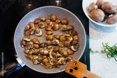 Obraz na płótnie Sauteed in olive oil small champignons with chopped garlic. Mushroom cooking in frying pan top view. w salonie