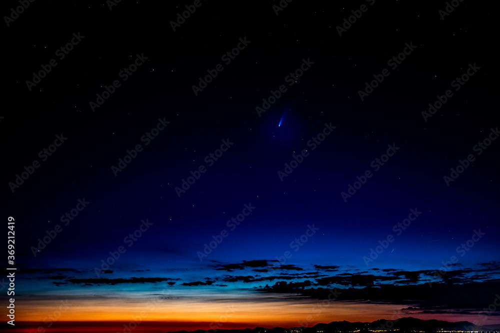 The comet Neowise appears in the sky, close to the horizon.