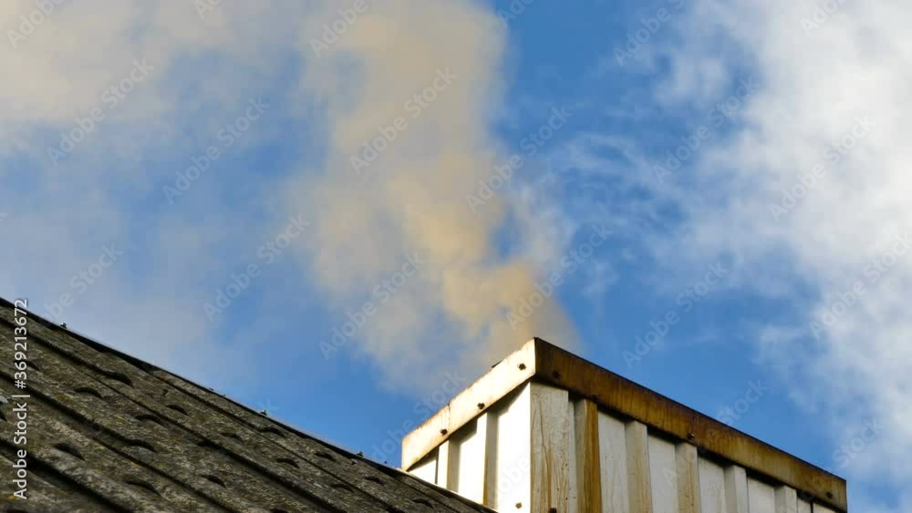 smoke from the chimney into the atmosphere, against a background of blue sky smoke from the chimney into the atmosphere, against a background of blue sky