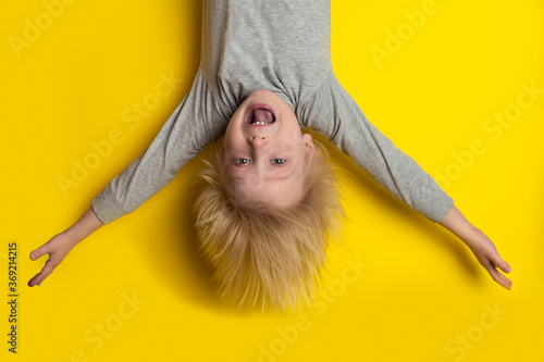 Φωτογραφία Happy blond boy hanging upside down with arms outstretched