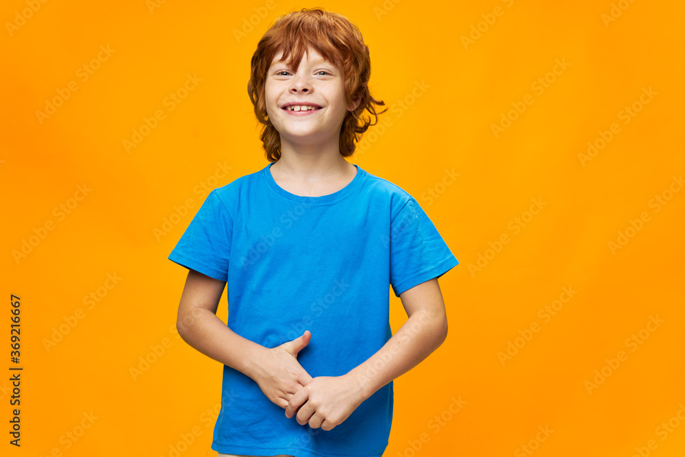 Happy red-haired child in a blue T-shirt touches his fingers Happy red-haired child in a blue T-shirt touches his fingers